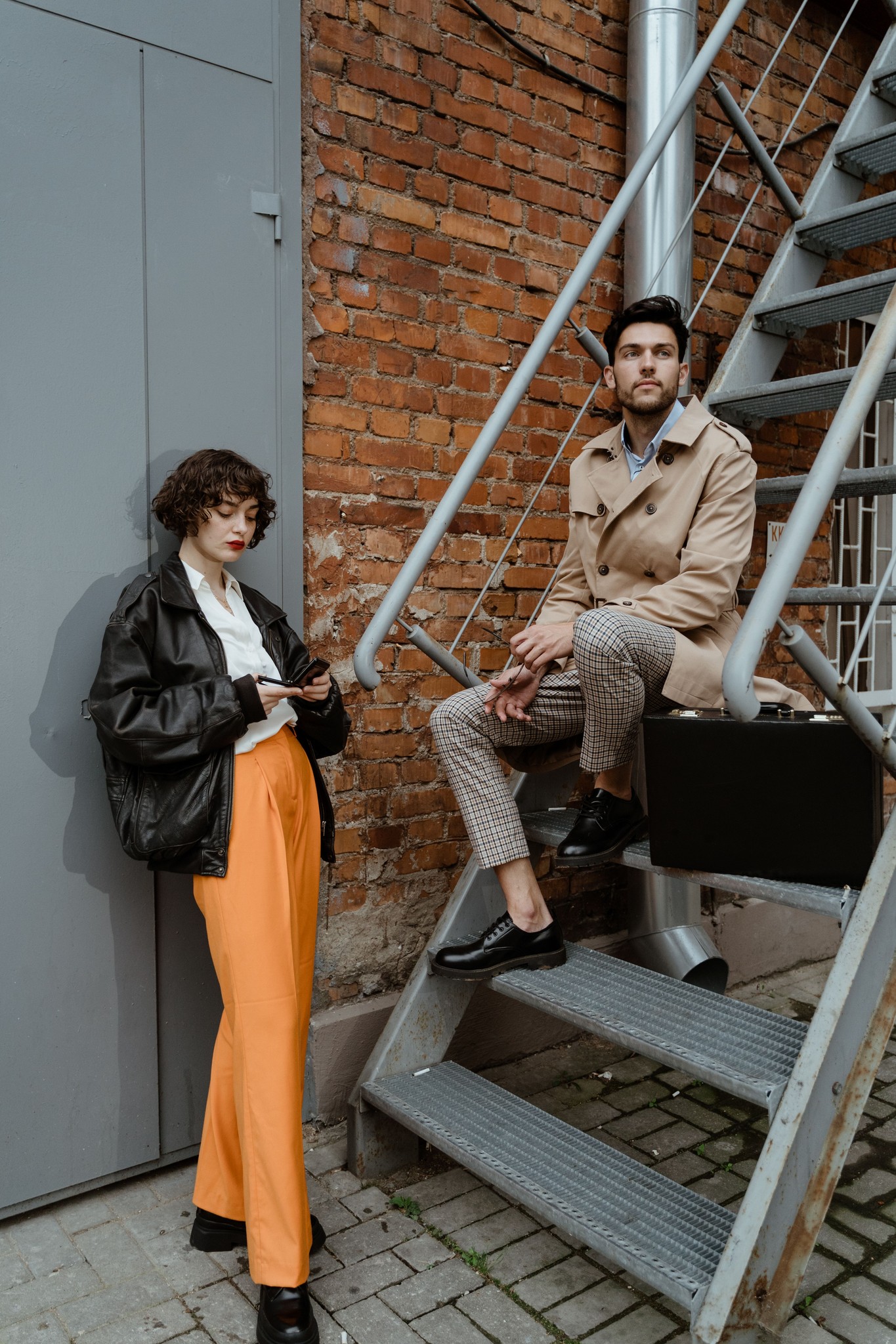 Two people sitting outside a brick building